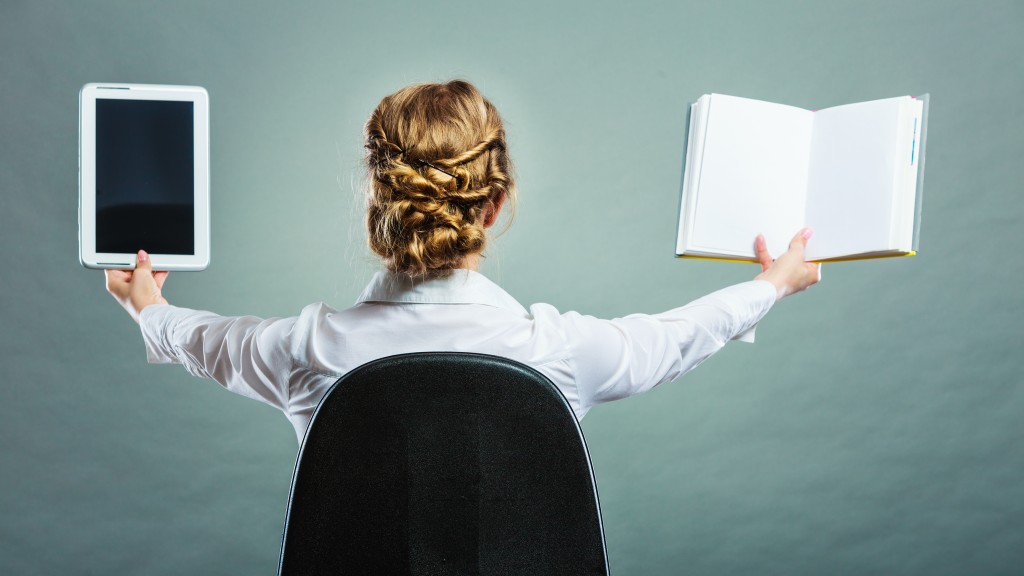 Ebook vs book. Woman sitting on chair holding traditional book and e-book reader tablet touchpad pc back view grunge background.